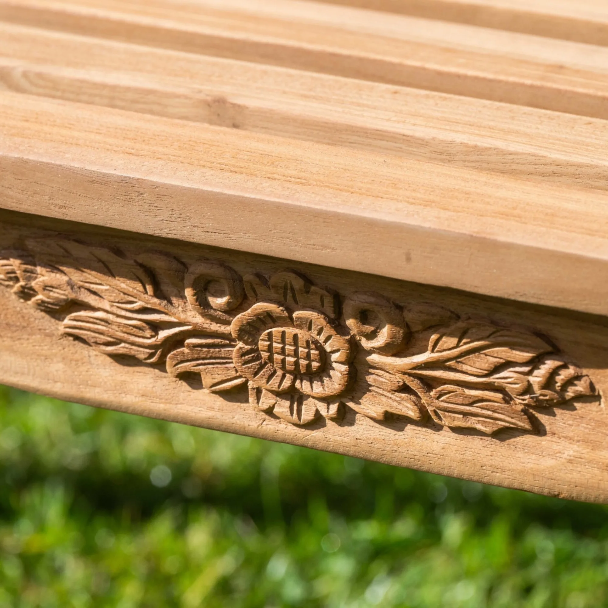 The teak bench positioned on a stone patio beside planters